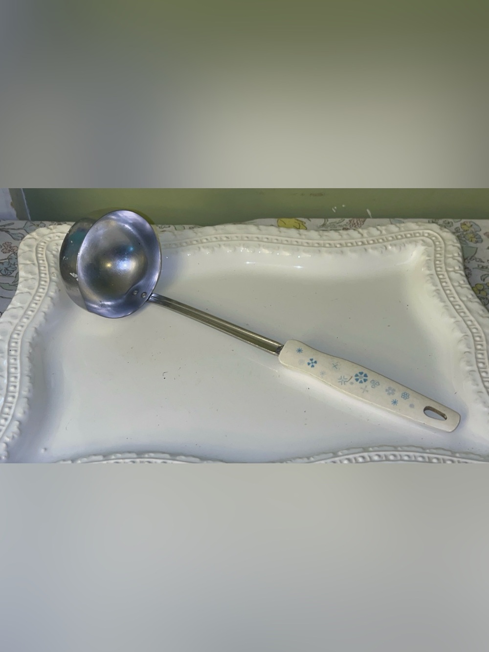 Vintage stainless steel soup ladle with blue floral motif